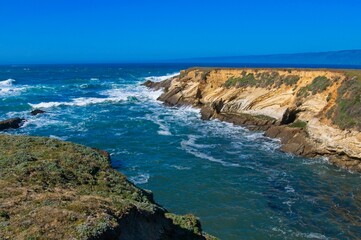 Fototapeta na wymiar Ocean waves crash into the California coast creating interesting textures in the rocks face.