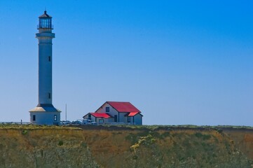 The Point Arena Lighthouse stands as a sentential while the waves crash over the rocky shoreline on the California coast.