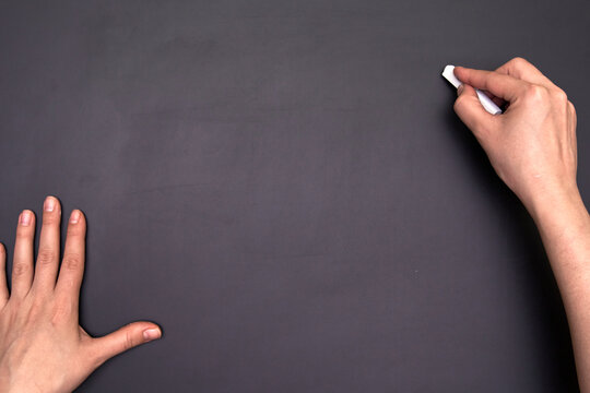 Close-up Of Hands Writing With A Chalk On An Empty Blackboard. Many Copy Space For Text.