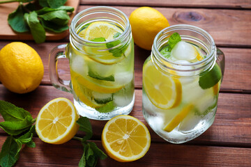 Fresh homemade citrus lemonade with lemons, mint and ice on a rustic wooden table. Summer cold refreshing drinks. Close-up, selective focus