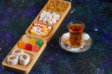 Delicious Turkish delights with tea on colorful background
