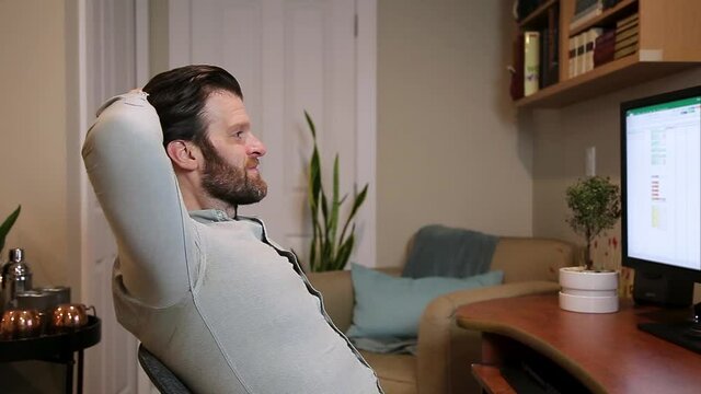 Man leaning back in chair satisfied with finishing a project or other success working from home desktop computer. HD 24FPS.