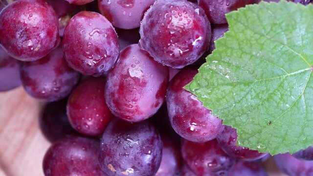 Top view rotate Red grape fruit with leaves closeup, Fresh Red grape fruit with green leaves in the garden.