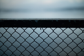 Chainlink fence against water and sky