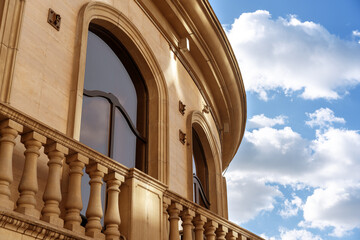 The facade of the building with large windows in the classic Baroque style on a sunny day.