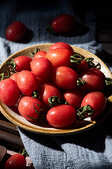 Fresh cherry tomato in plate on wooden background