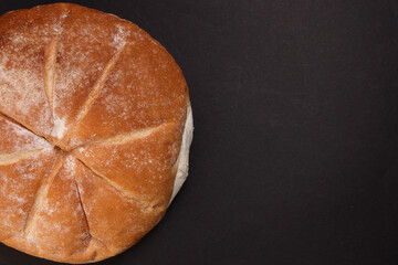 Freshly baked bread loaf round on black background