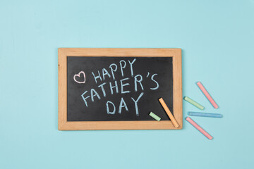 Happy Fathers Day written on chalkboard with chalk on blue background