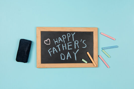 Happy Fathers Day written on chalkboard with chalk on blue background