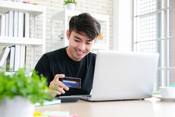 Man paying with credit card on notebook at home office.