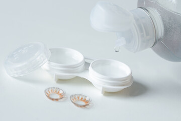 Contact lenses, case and bottle with solution on white background. Eye health and care. Selective focus