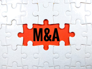 Selective focus.Word M and A (mergers and acquisitions) with jigsaw puzzle on red background.Business concept.