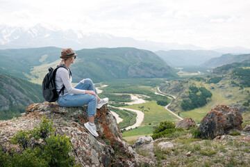 Mature woman backpacker enjoy the view at mountain peak. Adult woman meditating, thinking outdoors.