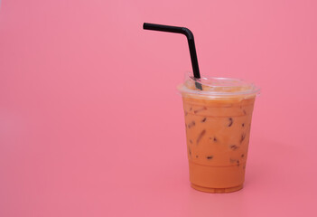 Plastic cup of ice milk tea on pink background