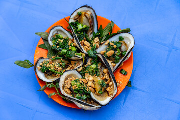 Plate of delicious grilled ark clams topped with scallion and peanuts