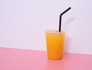 Glass of orange juice over white and pink background
