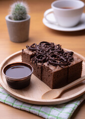 Sweet and tasty chocolate cake with chocolate sauce on table