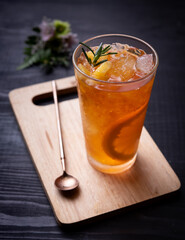 Orange iced tea in a glass on a rustic wooden background.