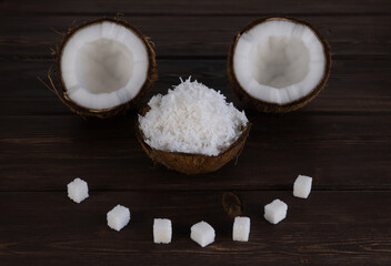 split coconut on wooden planks. selective focus. nut peel is filled with coconut shavings. Coco, ripe palm fruit. fruits are laid out in the form of a cheerful muzzle. faces made of food