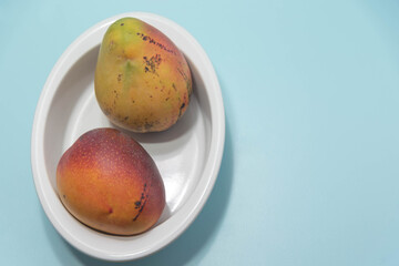 Fresh pink mango fruit on blue background