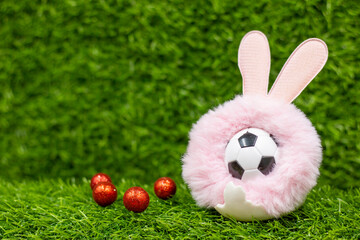 Soccer ball for Easter Holiday with Easter eggs decoration on green grass