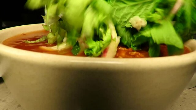 Putting vegetables on the noodle. Laksa a popular dish in Malaysia