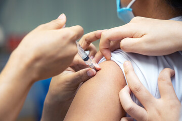 Close-up hand of doctor or nurse holding syringe making a vaccination to the shoulder of patient, Coronavirus (covid-19) vaccine disease during pandemic prevetion.