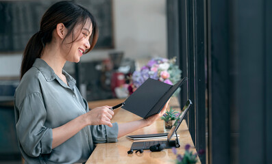 Beautiful asian woman learning and working on tablet at cafe.