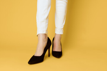 Female legs black shoes fashion attractive look white jeans yellow background