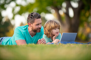 Father and son school boy with laptop. Dad and child use notebook tablet outdoors.