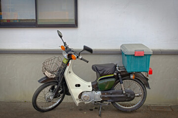 A motor scooter in front of a building wall
