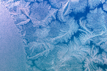 Natural texture of ice on a frozen window in blue light. Christmas background