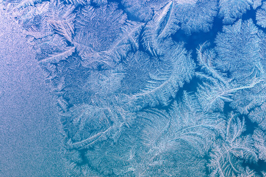 Natural texture of ice on a frozen window in blue light. Christmas background