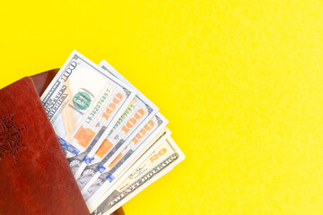 Business success concept. Saving money concept. Dollars in a brown wallet on a bright yellow trending background