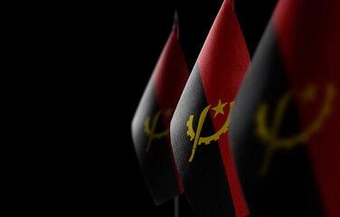 Small national flags of the Angola on a black background