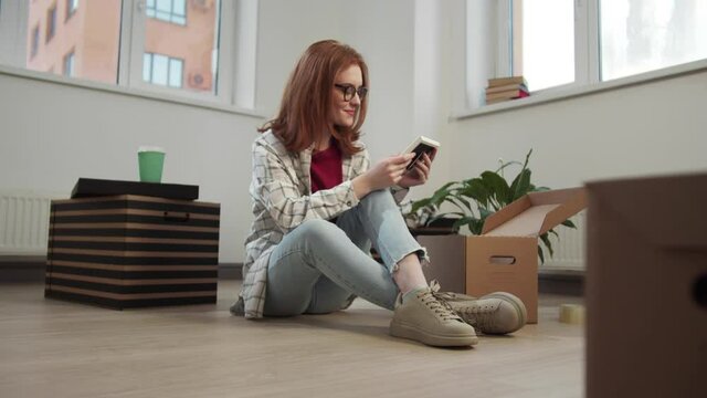 Young woman unpacking and looking at photos while sitting on the floor
