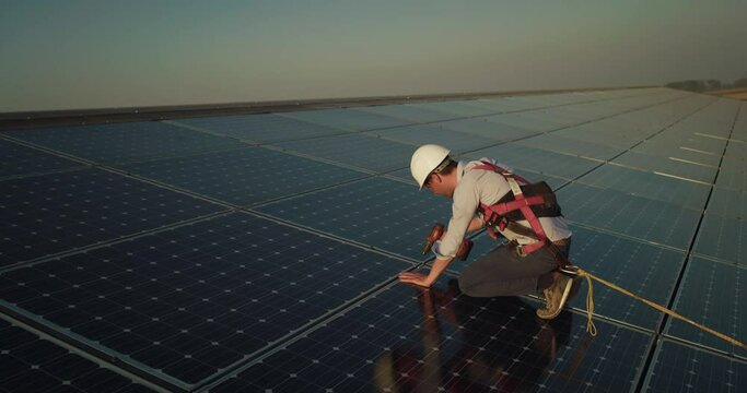 Cinematic shot of assistance technical worker in uniform checking operation and efficiency of photovoltaic solar panels on roof at sunset. Concept: sustainable renewable green, bio eco clean energy.