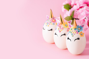 Unicorn eggs. Three Easter eggs in the form of a unicorn and a branch of a blossoming apple tree on...