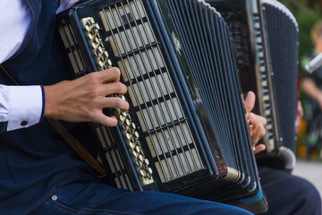 playing the musical instrument button accordion. The guy plays the button accordion, - obrazy, fototapety, plakaty