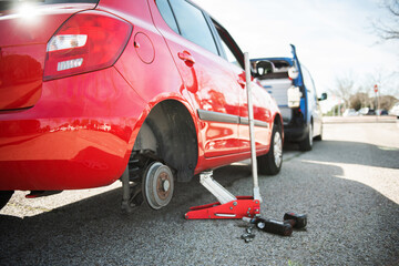 lifted car without wheel.car on the road receiving assistance.car on the road waiting for assistance.Hydraulic car jack lift the new car for change the tyre