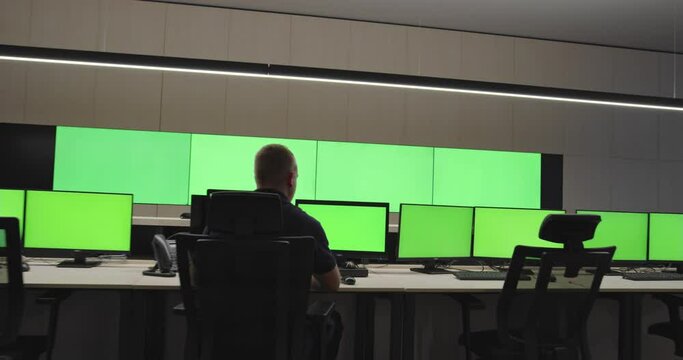 System Security Specialist Working at System Control Center. Room is Full of Green Screens, Chroma screen and security
