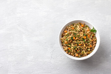 Delicious vegetarian buckwheat with cabbage, carrots, onions, nuts and herbs on a light gray textured background, top view, space. Homemade diet healthy food	