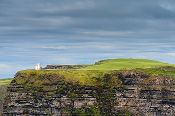 Fototapeta na wymiar View O'Briens tower on Cliff of Moher, county Clare, Ireland. Epic landscape with magnificent scenery. Irish landmark and popular tourist attraction. Atlantic ocean, Cloudy sky. Sunny day