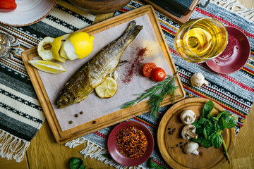 Baked fish seabass with fish spices, wine and salad. Seafood in restaurant. Top view. Healthy eating