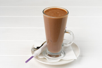 Glass cup of cocoa drink on white wooden table