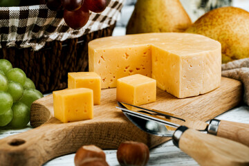 Cheese dish with organic cheeses, fruits, nuts on a wooden background. Delicious cheese snack