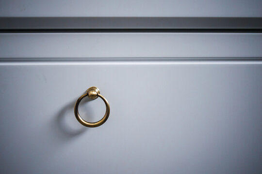 round metal handle from a copper-colored cabinet attached to a white drawer