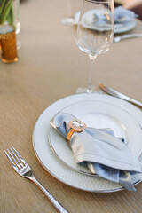 a wooden table set with white plates and blue napkins. Fresh flowers on the table on the background of the dome from the windows