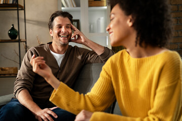 Young couple sitting and talking at home. Woman and man flirting and laughing..