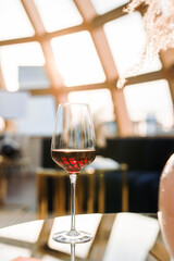 a large glass glass with a red one hangs on the coffee table against the background of the window, from which the sun shines.